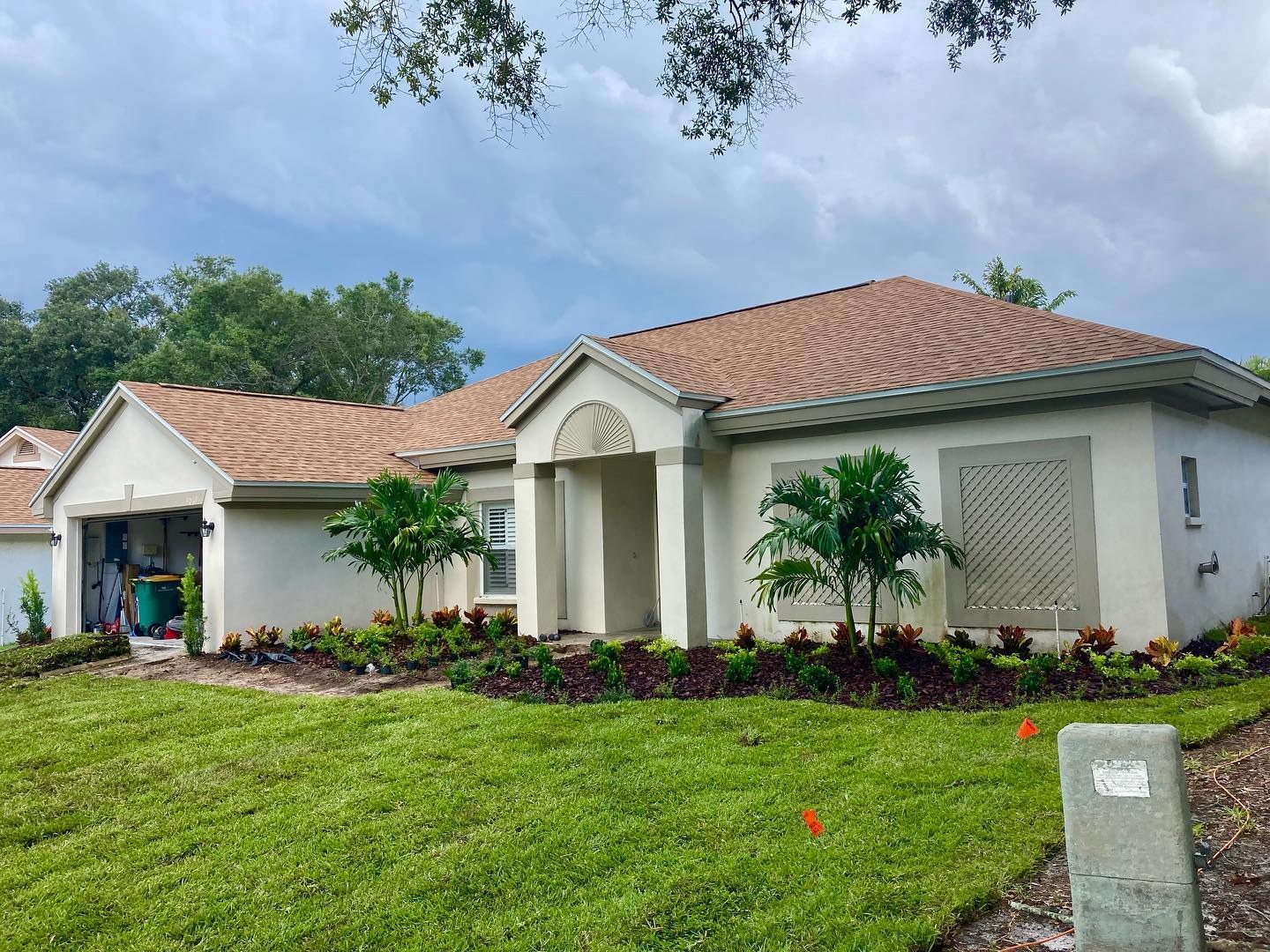 A Millennium front-yard install with fresh sod, palms and wide, layered planting beds