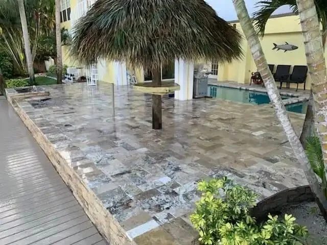 A finished paver patio in a Tampa Bay backyard with tight joints, a clean edge restraint, and a seat wall, built on a properly compacted base