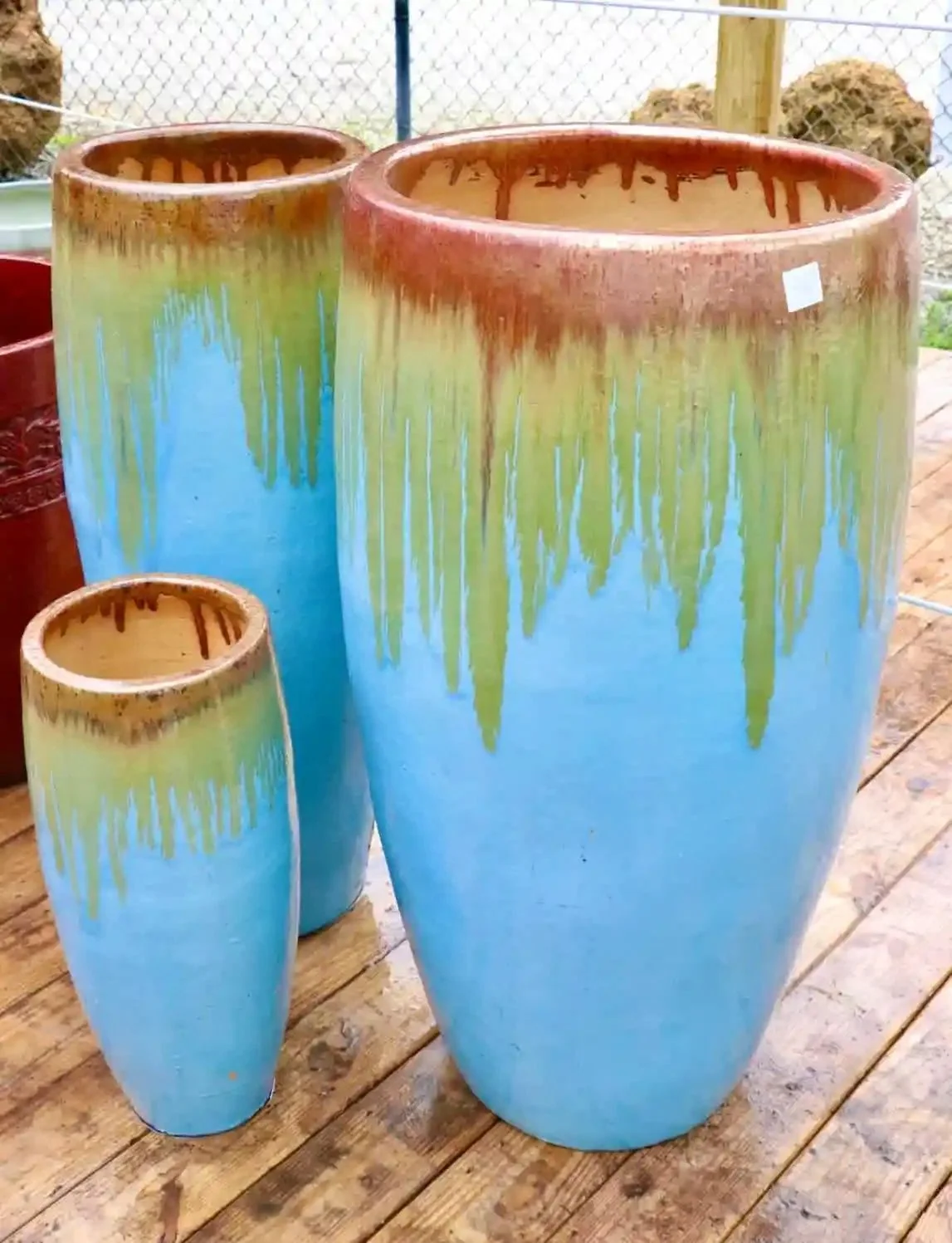 Three glazed ceramic tall egg pots with sky-blue glaze and a brown drip rim, displayed at Millennium's Odessa nursery