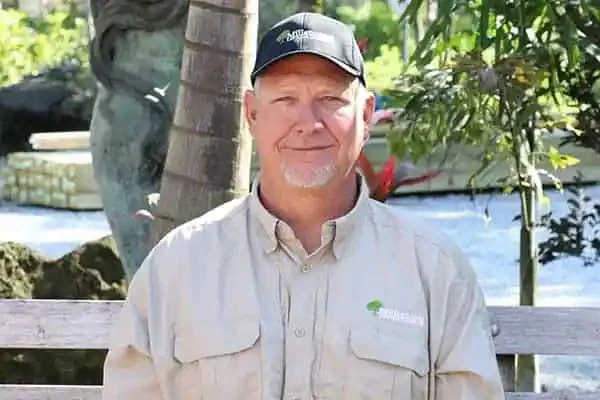 Dennis Slininger, Innisbrook Property Manager, smiling outdoors in a park-like setting with greenery behind him